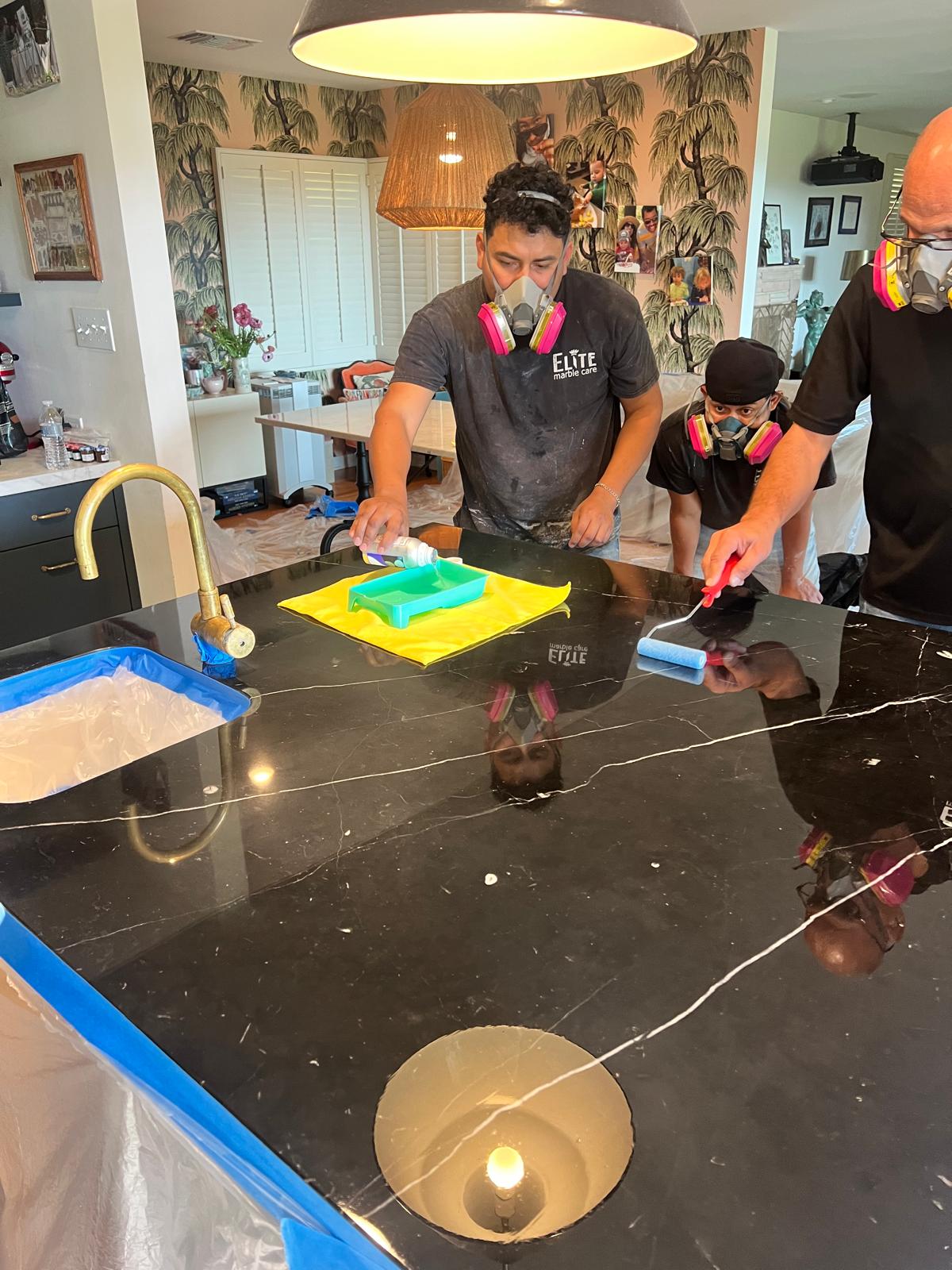Technician applying protection to a polished black marble countertop