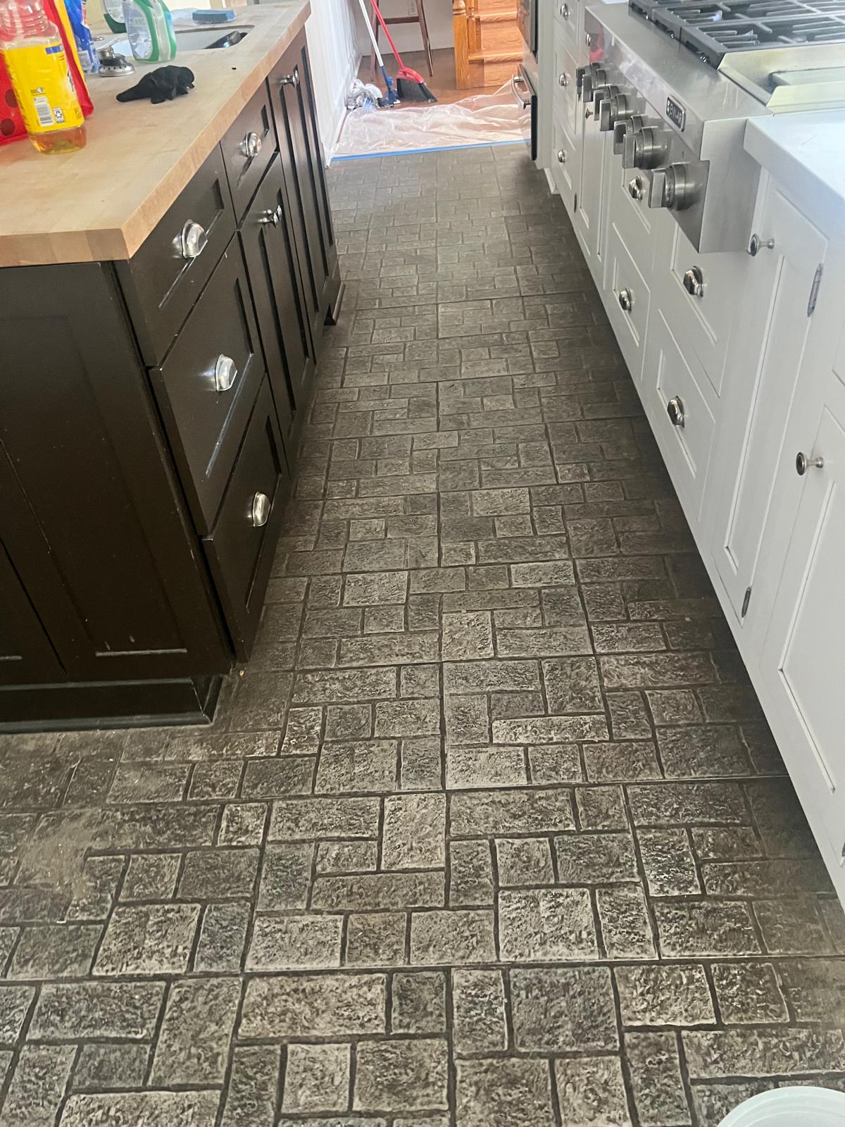Textured stone kitchen floor with embedded dirt before cleaning