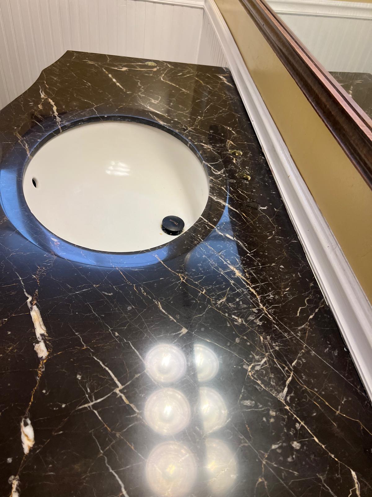 Dark marble vanity with visible dull spots and etching