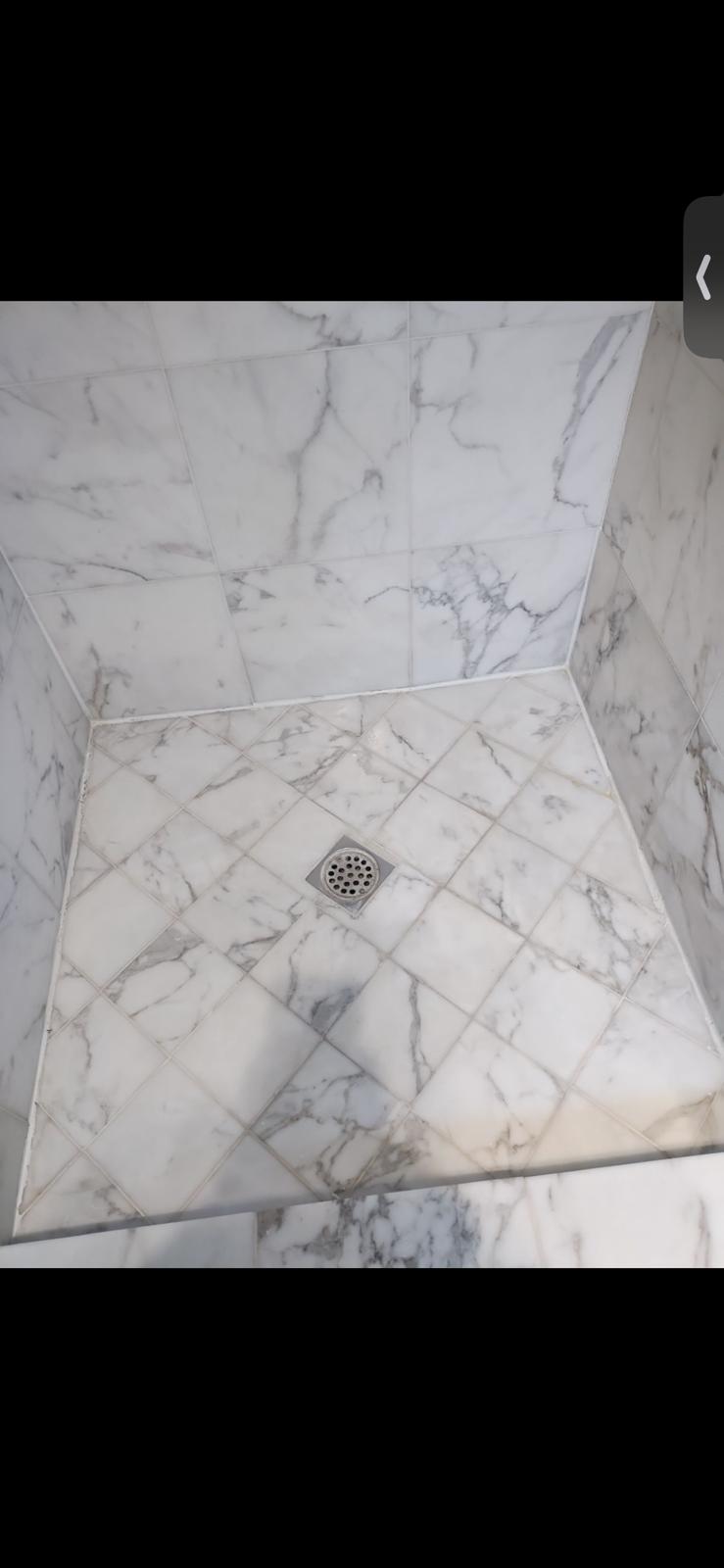 Marble shower with grout and caulk areas needing professional cleaning