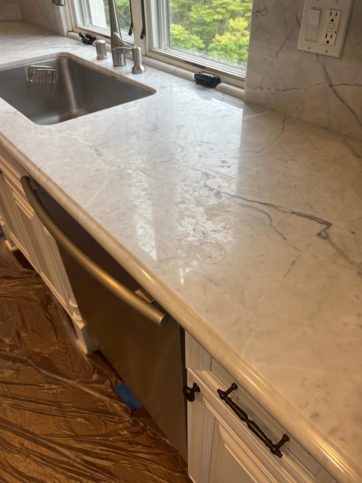 White marble countertop showing circular etch marks before polishing