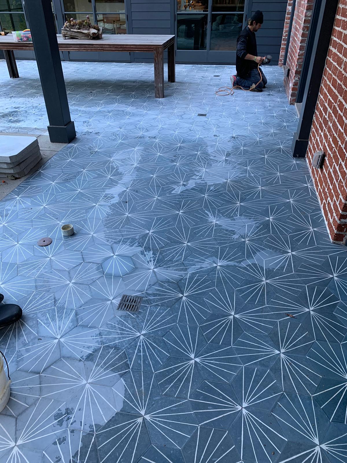 Technician honing patterned outdoor patio tiles with water